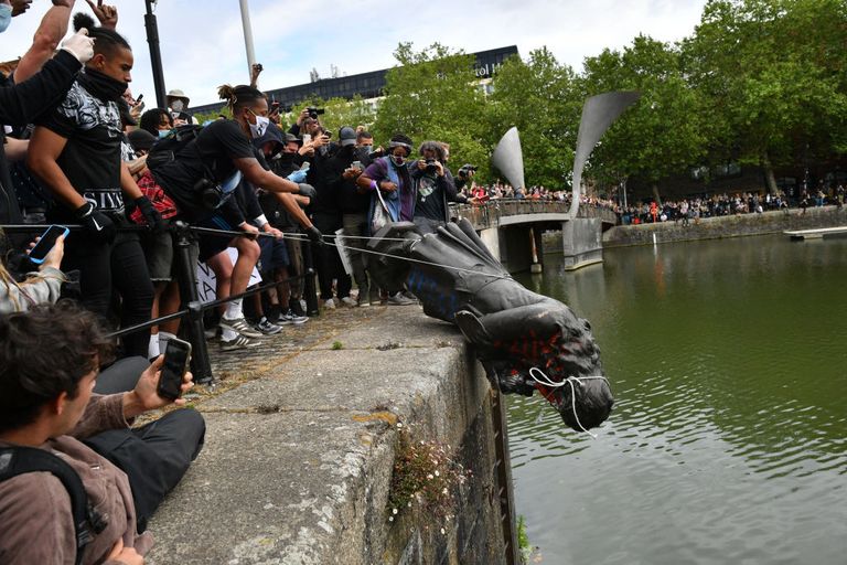 Protesters in Europe attempt to throw a statue into an urban body of water.