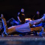 Two police officers stand behind a toppled confederate statue.
