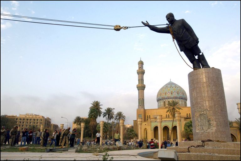 A statue of Saddam Hussein being toppled using ropes.